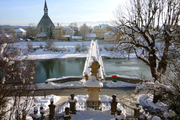 Winterfoto des Europastegs über die Salzach mit Stiftskirche Mariä Himmelfahrt im Hintergrund