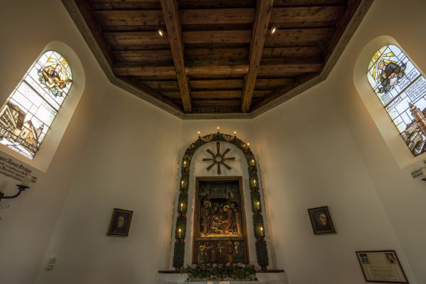 Innenaufnahme der Stille-Nacht-Kapelle mit Altarbild, kunstvoll gestalteten Fenstern und Sichtholzdecke
