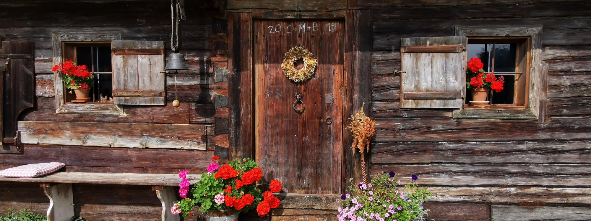 Hausfront der Bauernhofwanderung komplett in verwittertem Holzblock mit Hausbank