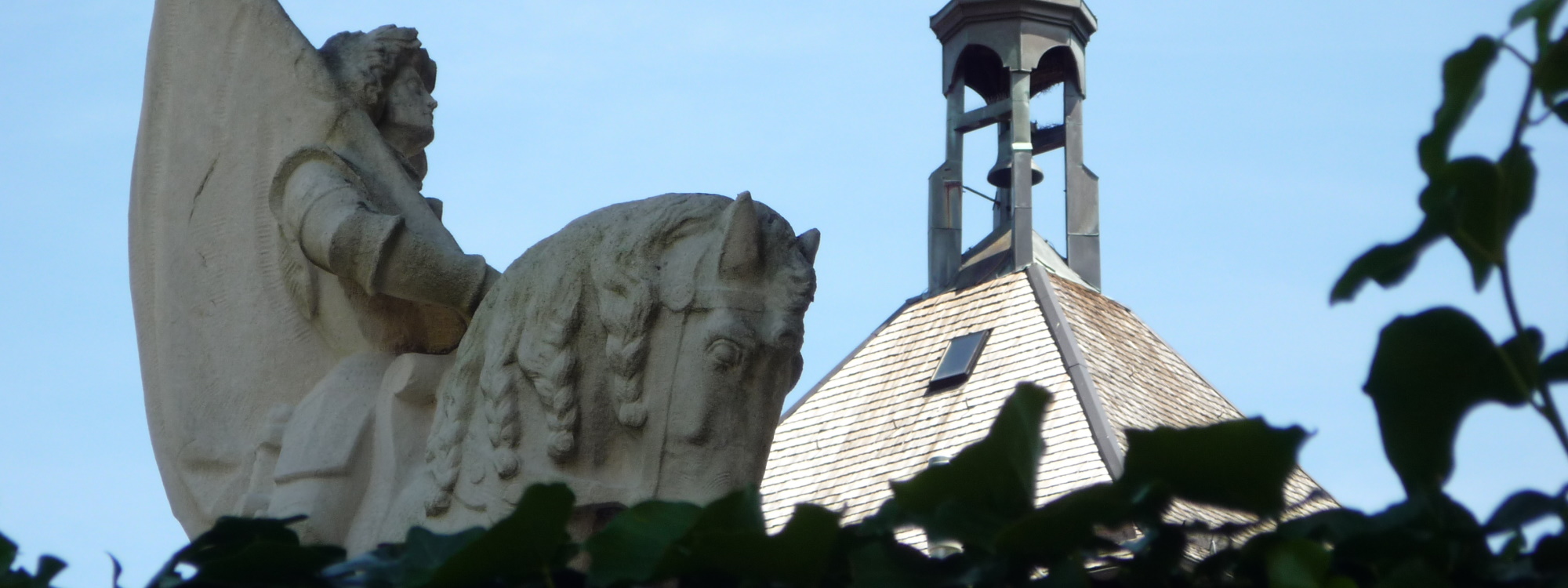 Detailaufnahme des Reiters am Kriegerdenkmal in Laufen mit Dach des Oberen Stadttors im Hintergrund