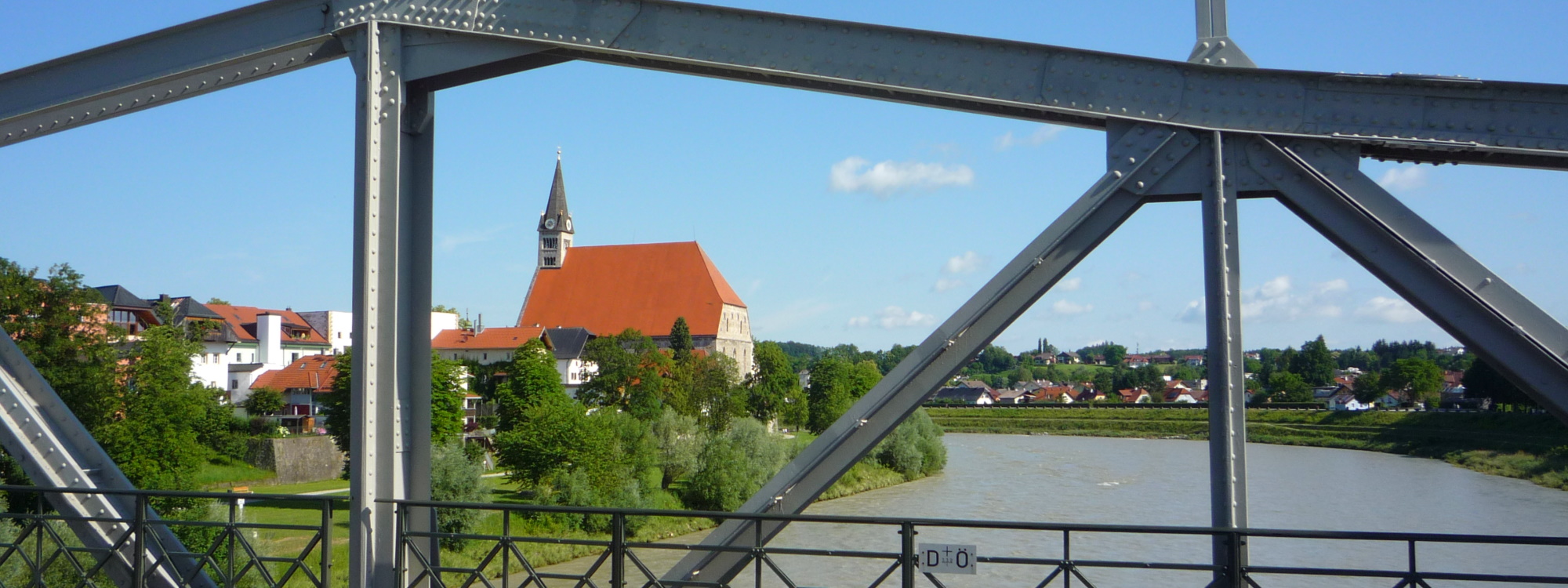 Ausschnitt der Salzachbrücke als Detail im Vordergrund mit Stiftskirche im Hintergrund